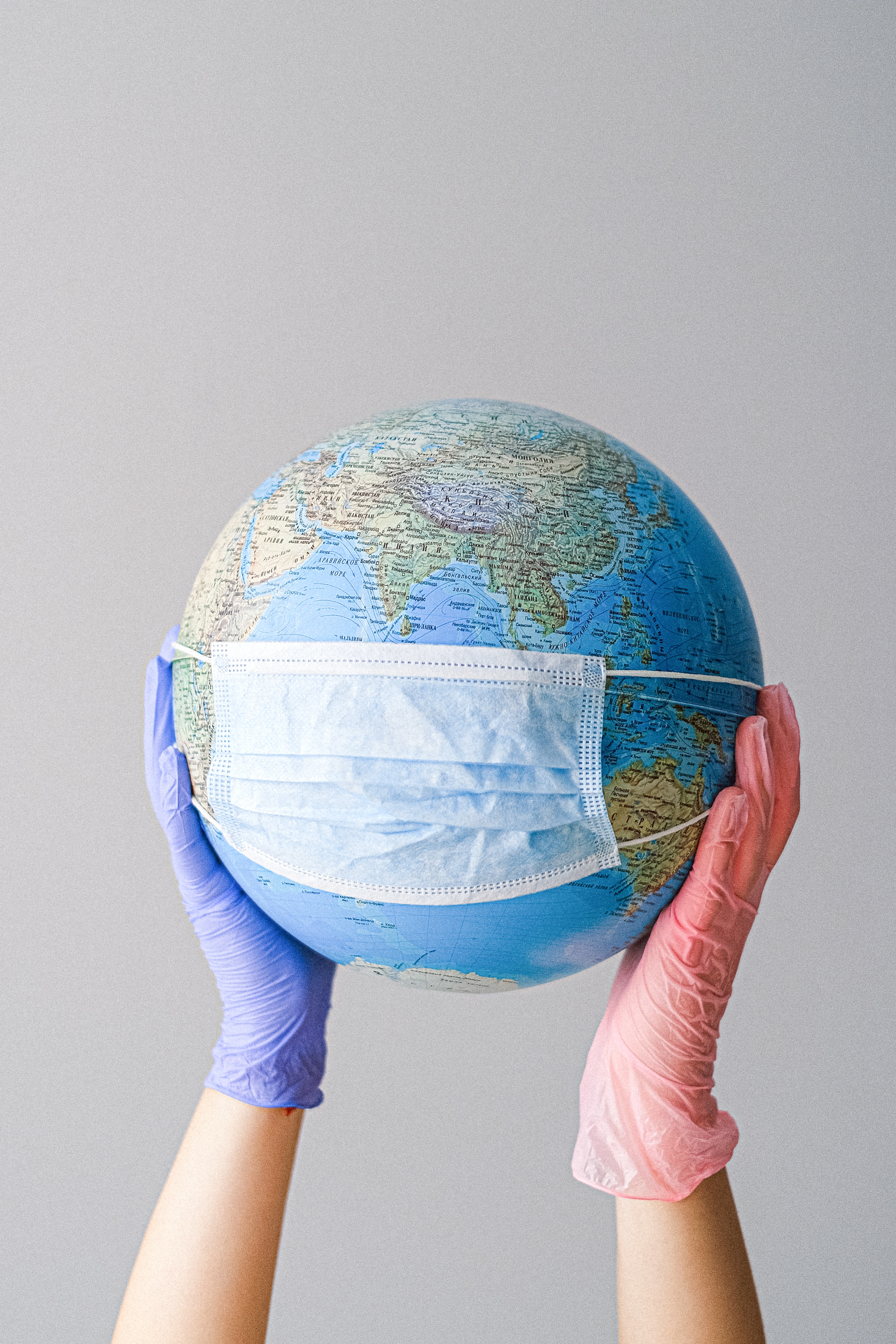 Hands with Latex gloves holding globe with mask